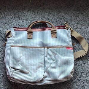 Skip Hop Striped Grey and White Diaper bag with red and beige accents.